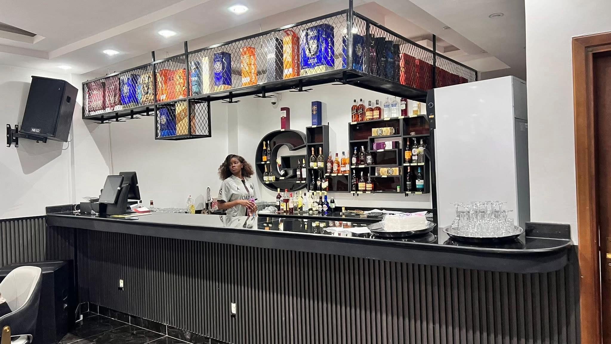 Le bar du Glen Lounge — monogramme « G » rétro-éclairé, casier à spiritueux suspendu